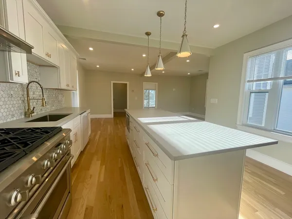a open kitchen with kitchen island a stove a sink a island and windows