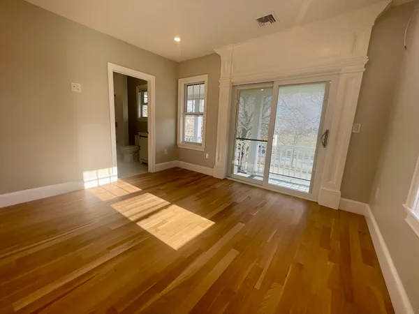 an empty room with wooden floor and windows