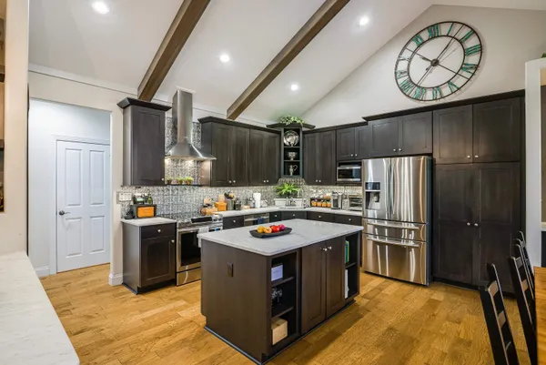 a kitchen with kitchen island stainless steel appliances a stove refrigerator sink and cabinets