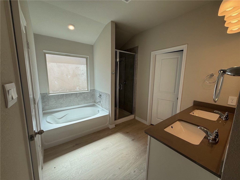 6117 Eldora Drive College Station, TX 77845 - Photo 7 of 8 Full bath featuring a bath, a stall shower, light wood-style flooring, double vanity, and lofted ceiling