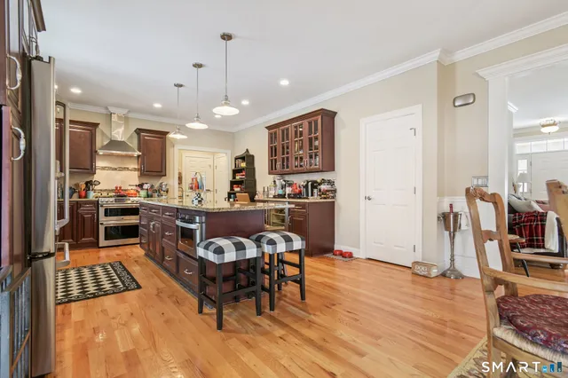 a kitchen with stainless steel appliances granite countertop a stove top oven a sink a dining table and chairs with wooden floor