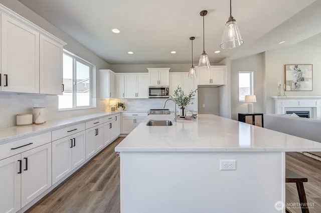 a large white kitchen with kitchen island a sink a center island stainless steel appliances and a window