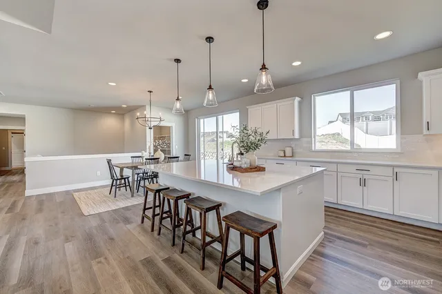 a kitchen with stainless steel appliances kitchen island granite countertop a table chairs sink and cabinets