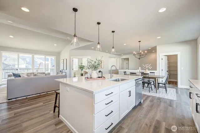 a kitchen with kitchen island a sink a stove a dining table and chairs with wooden floor