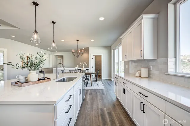 a large white kitchen with a large window a sink and stainless steel appliances
