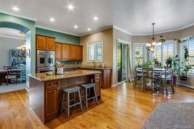 a kitchen with stainless steel appliances granite countertop a stove top oven a sink dishwasher and couches with wooden floor