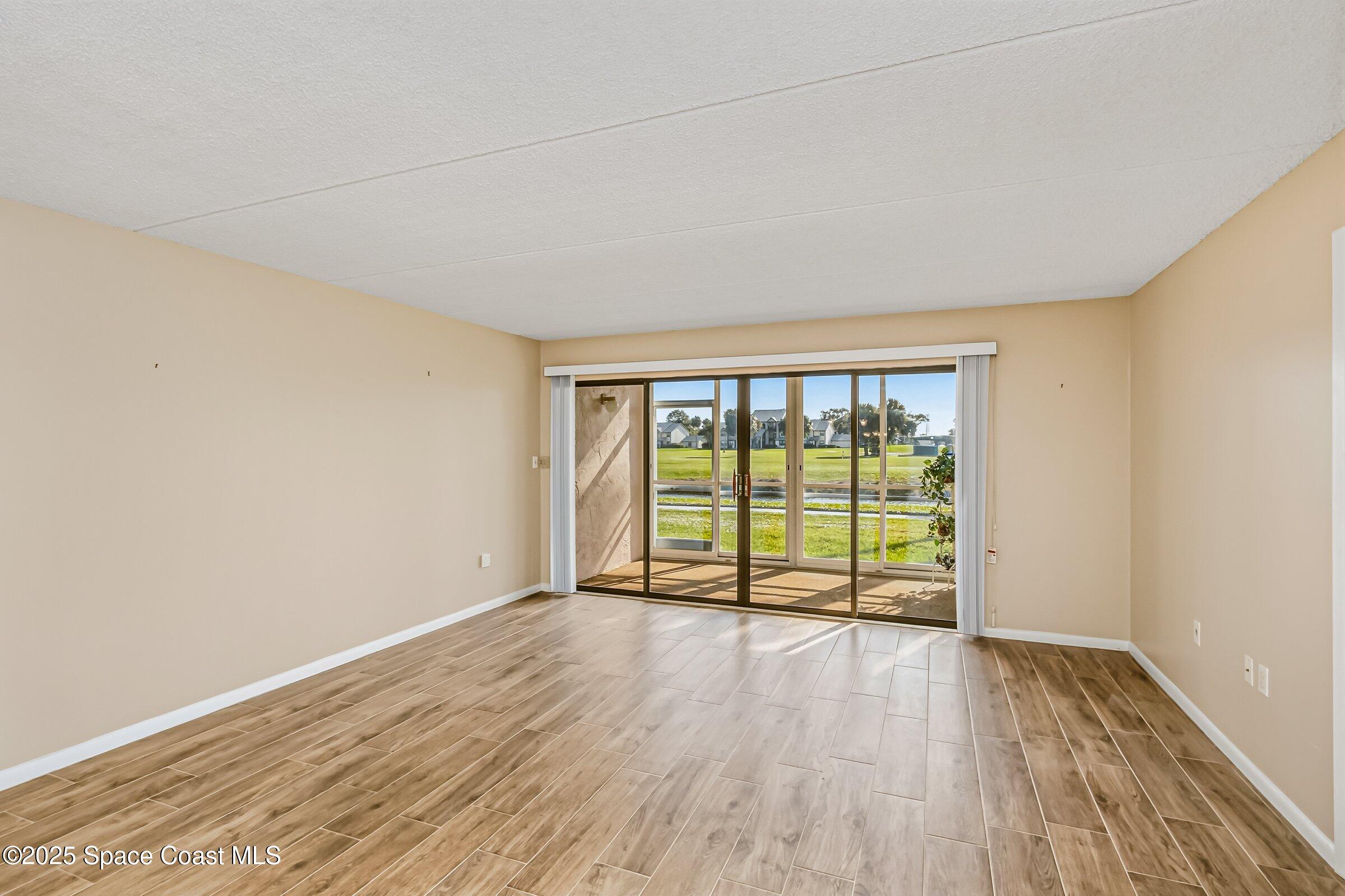 2727 North Wickham Road, Unit 11104 Melbourne, FL 32935 - Photo 17 of 55 wooden floor in an empty room with a window