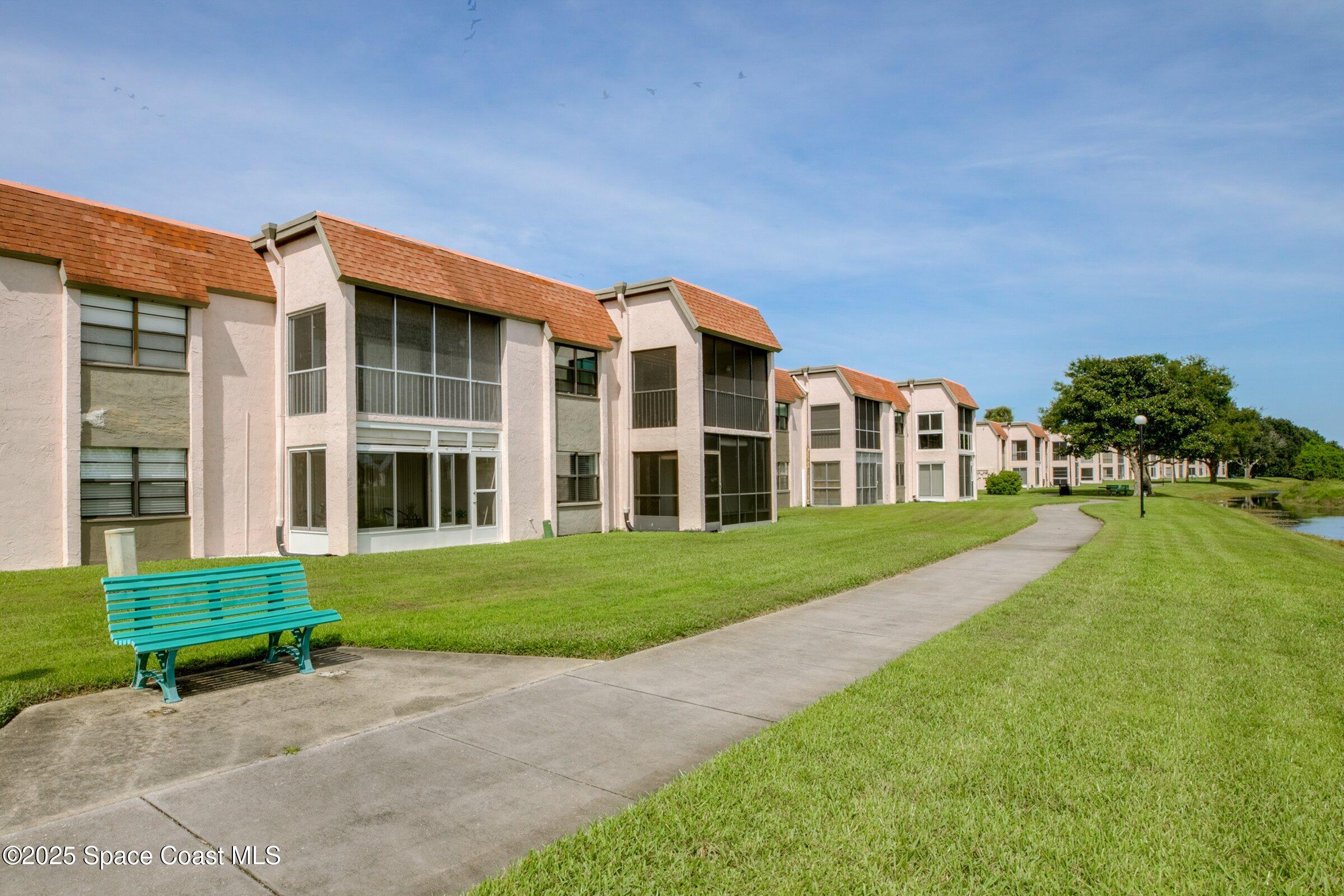 2727 North Wickham Road, Unit 11104 Melbourne, FL 32935 - Photo 33 of 55 a view of a big yard in front of a brick house with a large tree