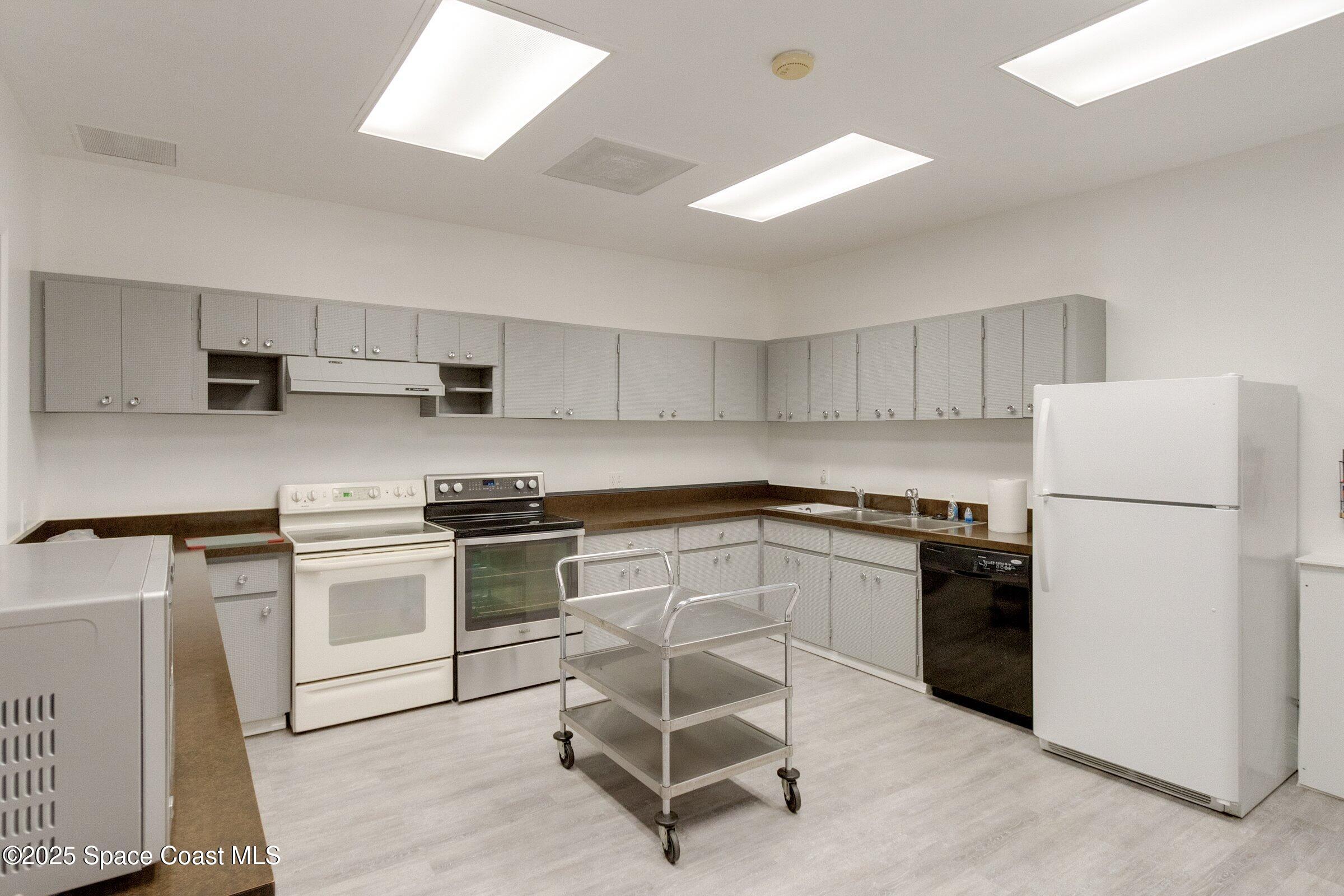 2727 North Wickham Road, Unit 11104 Melbourne, FL 32935 - Photo 46 of 55 a kitchen with a stove a refrigerator and white cabinets