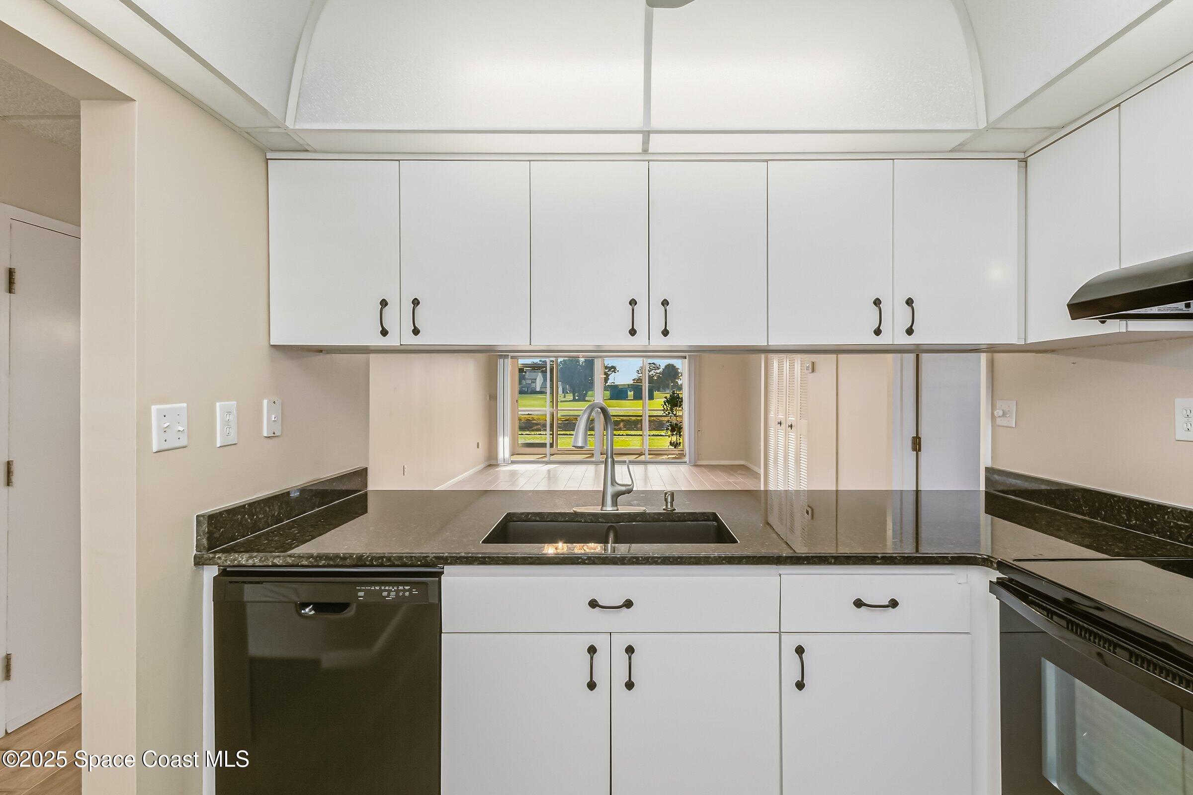 2727 North Wickham Road, Unit 11104 Melbourne, FL 32935 - Photo 9 of 55 a kitchen with granite countertop white cabinets and a stove