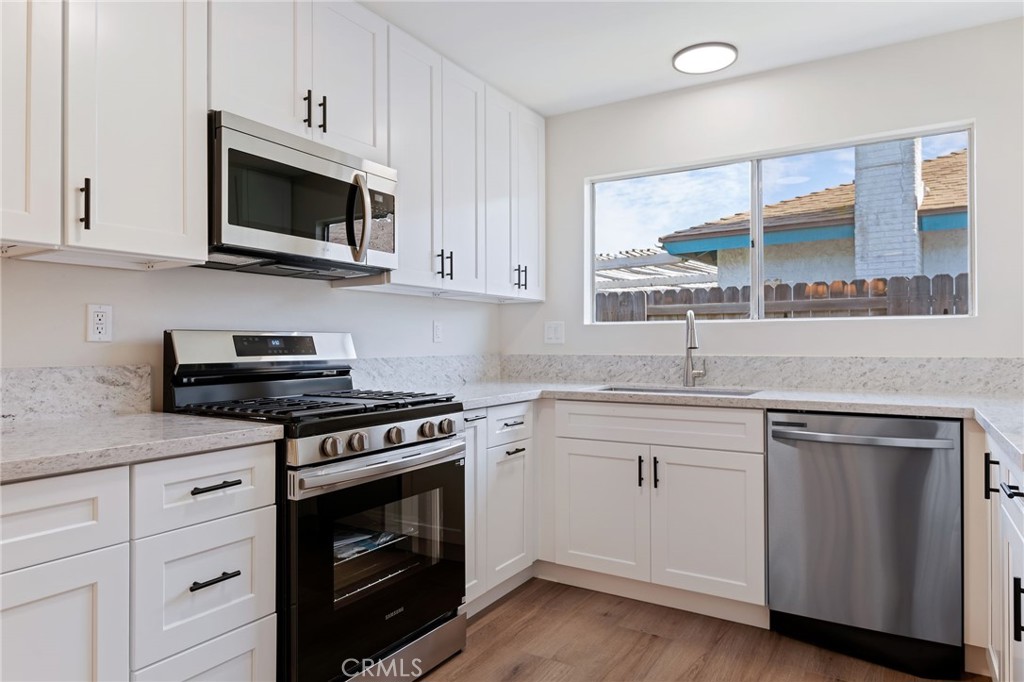 1077 Offshore Street Oxnard, CA 93035 - Photo 9 of 33 a kitchen with cabinets stainless steel appliances a sink and wooden floor