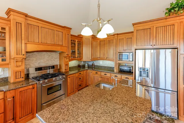 a kitchen with stainless steel appliances granite countertop a stove a refrigerator and a view of living room