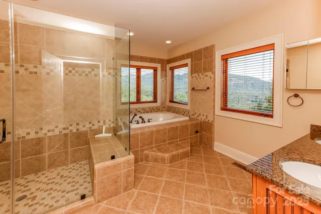a bathroom with a granite countertop sink a toilet a mirror and shower