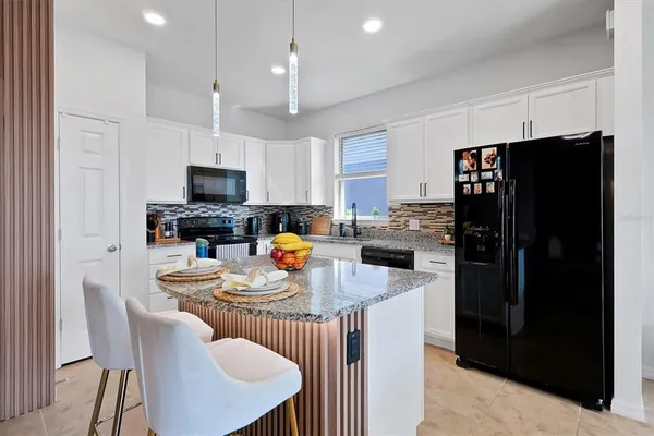 a kitchen with stainless steel appliances granite countertop a refrigerator a stove a sink a dining table and chairs