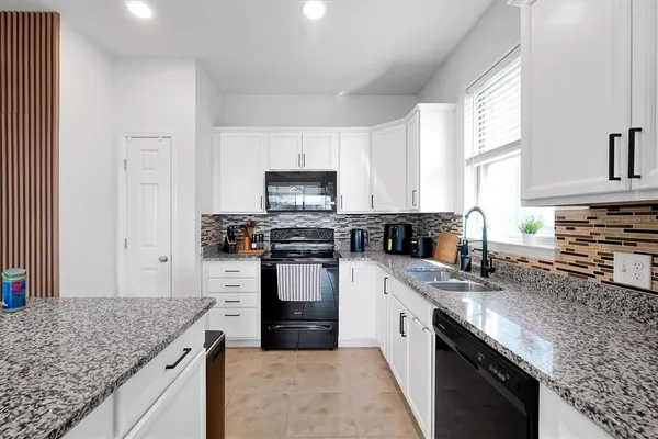 a kitchen with stainless steel appliances granite countertop a sink stove microwave and refrigerator