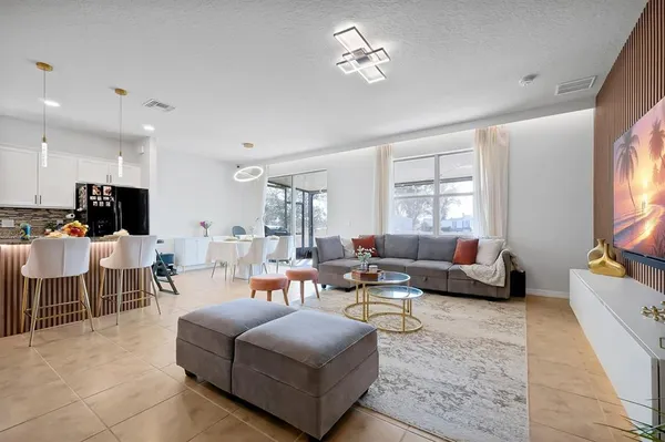 a living room with furniture kitchen view and a window