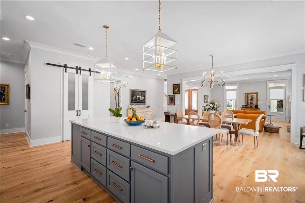 707 Cardamel Court Fairhope, AL 36532 - Photo 8 of 40 Kitchen featuring crown molding, a center island, a barn door, light hardwood / wood-style floors, and decorative light fixtures