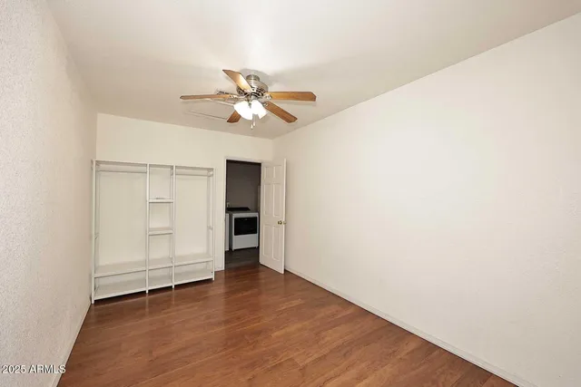 an empty room with wooden floor closet and ceiling fan
