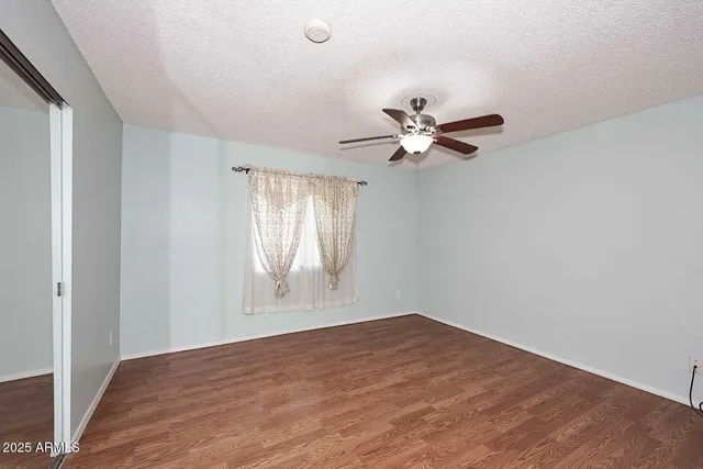 an empty room with wooden floor ceiling fan and windows