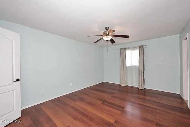 a view of a room with wooden floor and a ceiling fan