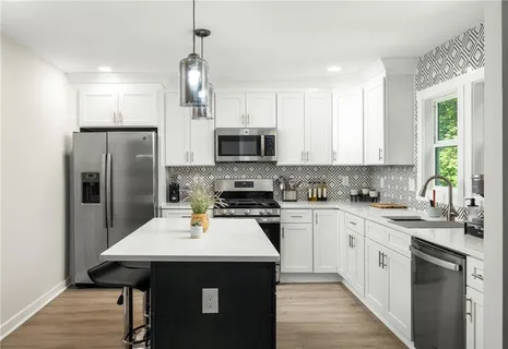 a kitchen with a sink a stove a refrigerator and white cabinets