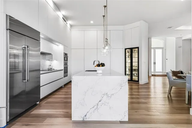 a kitchen with stainless steel appliances kitchen island granite countertop a refrigerator a oven a sink with island and chairs