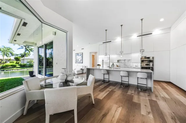 a dining room with stainless steel appliances kitchen island granite countertop a table chairs and a view of living room
