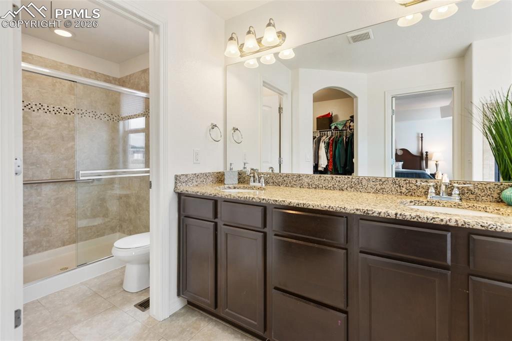 8458 Chasewood Loop Colorado Springs, CO 80908 - Photo 20 of 34 a bathroom with a granite countertop sink a toilet a mirror and shower
