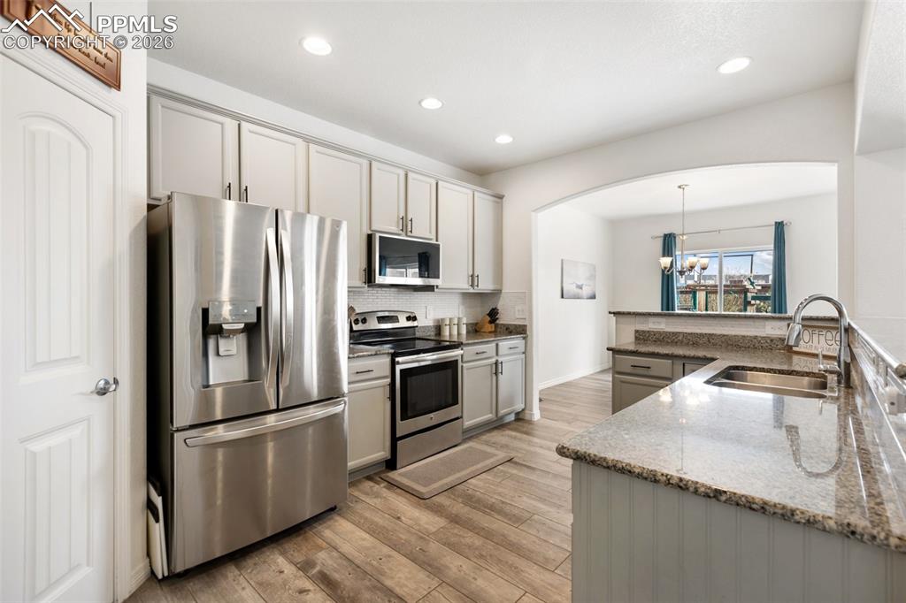 8458 Chasewood Loop Colorado Springs, CO 80908 - Photo 3 of 34 a kitchen with stainless steel appliances granite countertop a refrigerator a stove a sink and a microwave