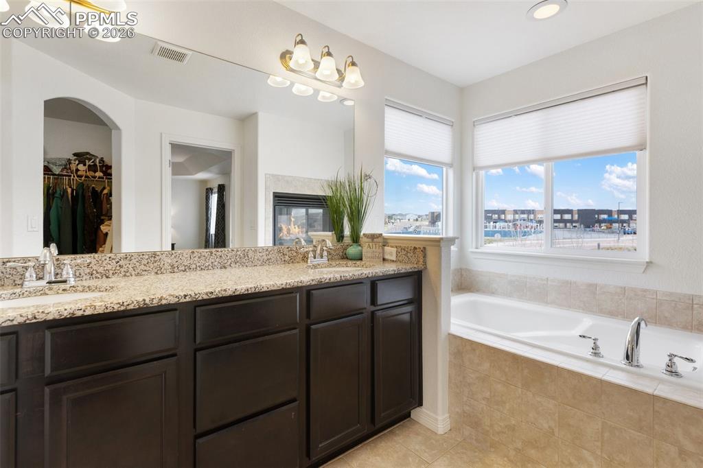 8458 Chasewood Loop Colorado Springs, CO 80908 - Photo 6 of 34 a bathroom with a granite countertop double vanity sink a bathtub and a mirror