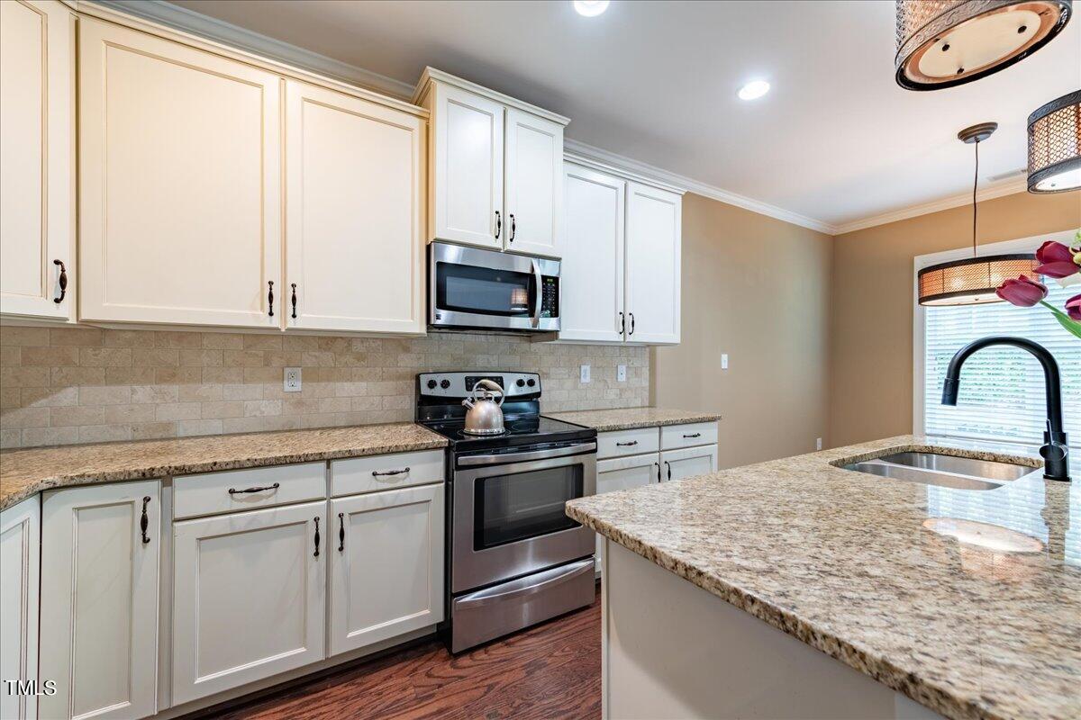 2115 Scarlet Maple Drive Raleigh, NC 27606 - Photo 14 of 32 a kitchen with granite countertop a sink a stove and cabinets