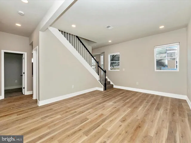 a view of an empty room with wooden floor and stairs