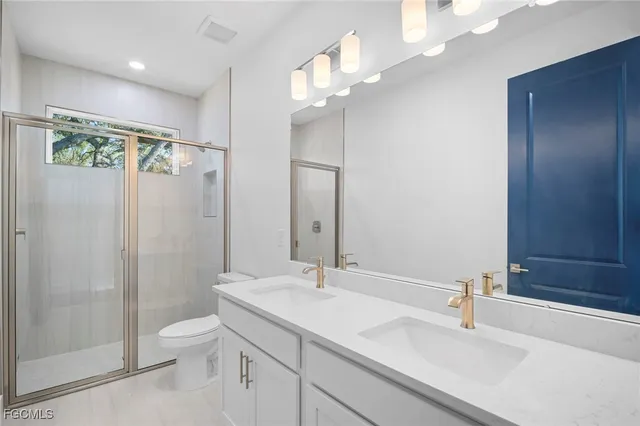 a bathroom with a sink a toilet a mirror and shower