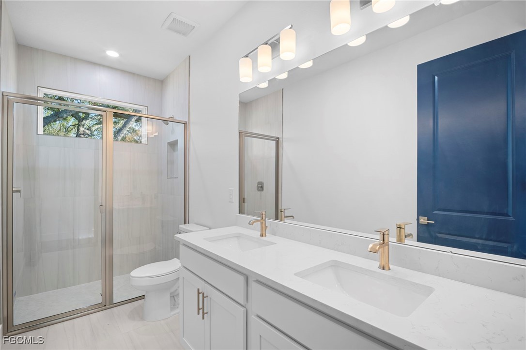 2816 Barry Road North Port, FL 34286 - Photo 26 of 36 a bathroom with a sink a toilet a mirror and shower