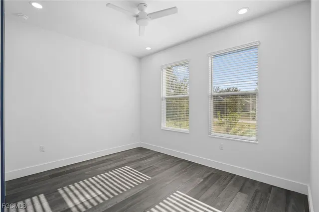 an empty room with wooden floor cabinet and windows