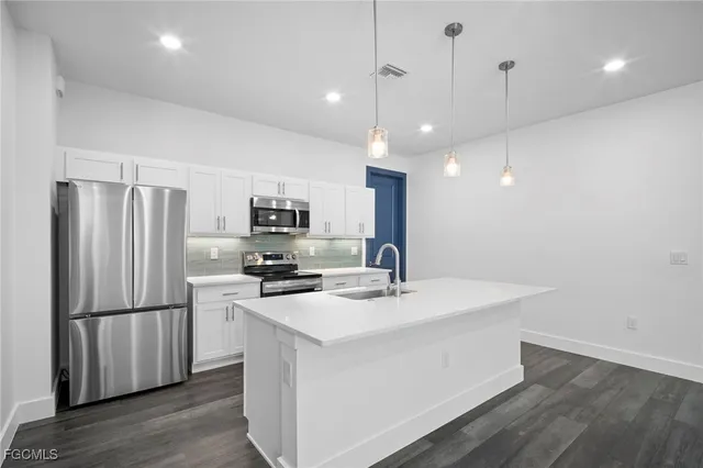 a kitchen with stainless steel appliances granite countertop a refrigerator a sink dishwasher a stove and a refrigerator with wooden floor