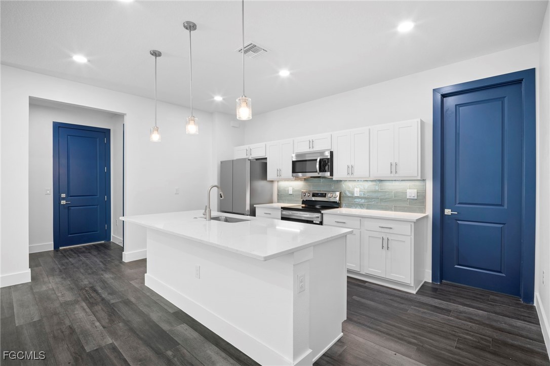 2816 Barry Road North Port, FL 34286 - Photo 9 of 36 a kitchen with stainless steel appliances a stove top oven a refrigerator a sink and white cabinets with wooden floor