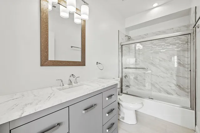 a bathroom with a granite countertop sink a toilet and shower
