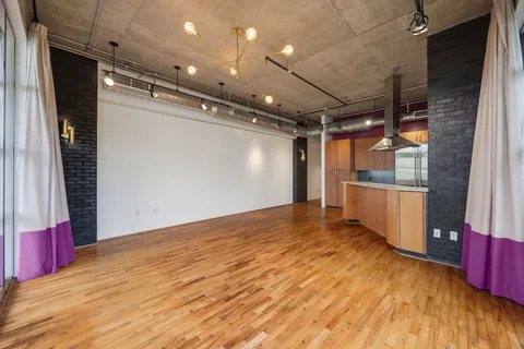 a view of an empty room with wooden floor and windows