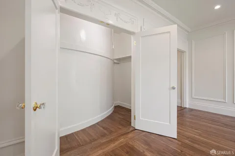 a view of an empty room with wooden floor and closet
