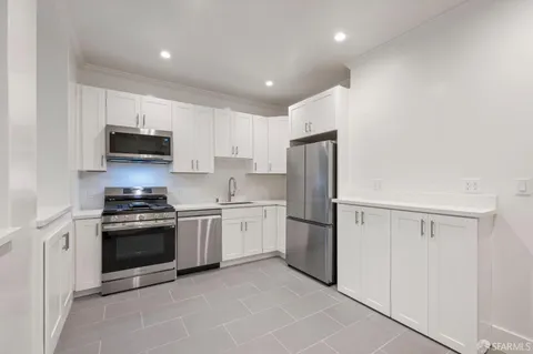 a view of kitchen with white cabinets and refrigerator