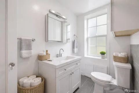 a bathroom with a sink toilet vanity and window