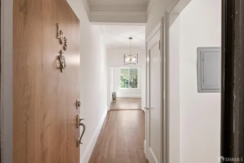 an empty room with wooden floor cabinet and windows