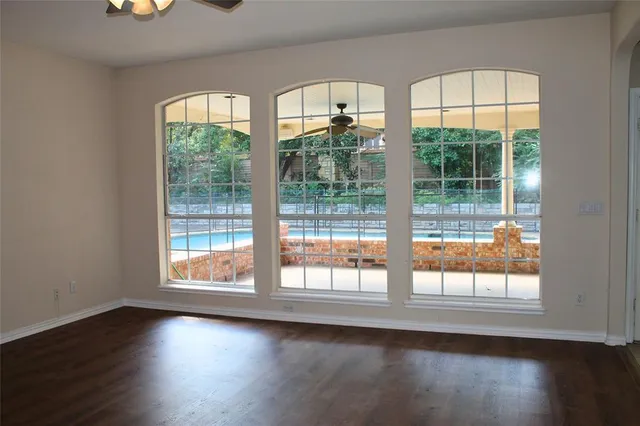 a view of an empty room with a window and wooden floor