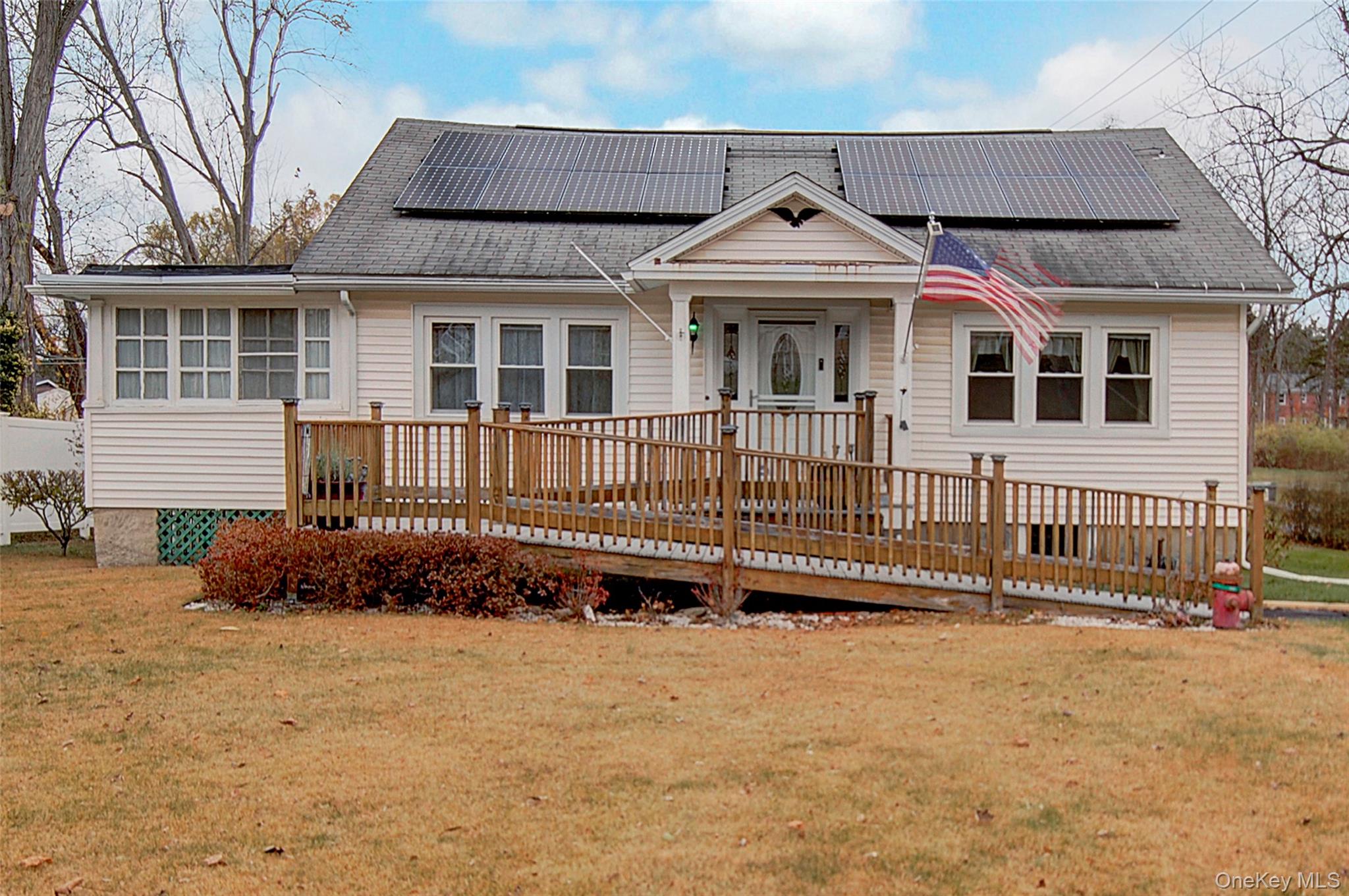 85 Overocker Road Poughkeepsie, NY 12603 - Photo 1 of 1 View of front facade with a front lawn, a wooden deck, roof mounted solar panels, and a shingled roof