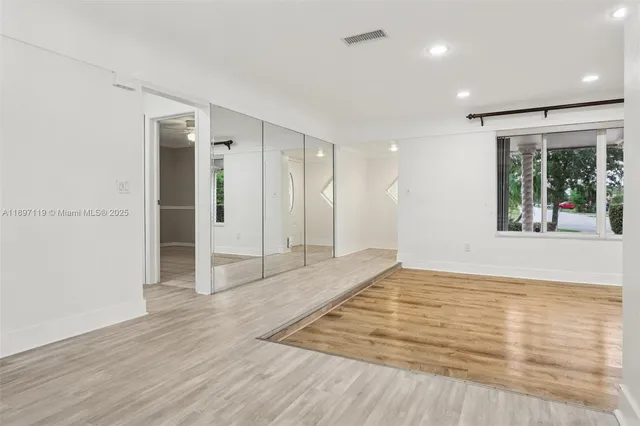 a view of a hallway with wooden floor and a kitchen space