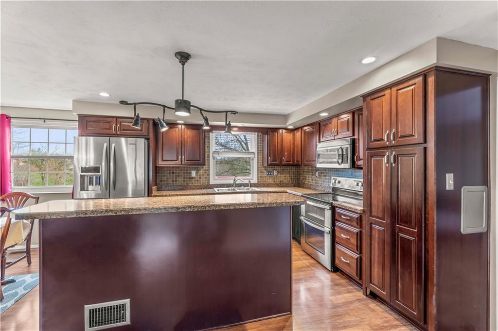 191 Deer Drive Washington, PA 15301 - Photo 10 of 33 a kitchen with stainless steel appliances granite countertop a refrigerator a sink dishwasher a stove and a dining table with wooden floor
