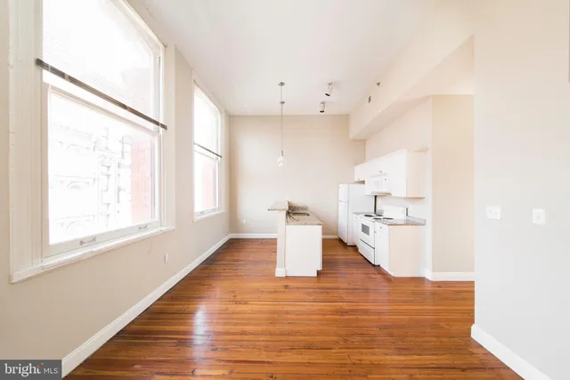 a kitchen with stainless steel appliances granite countertop a stove a sink dishwasher and a refrigerator with wooden floor