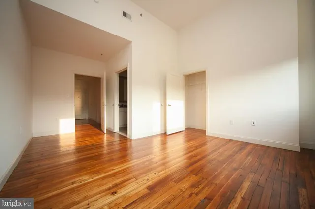 an empty room with wooden floor and windows
