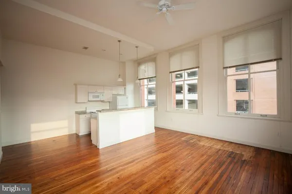 a view of kitchen and empty room with wooden floor